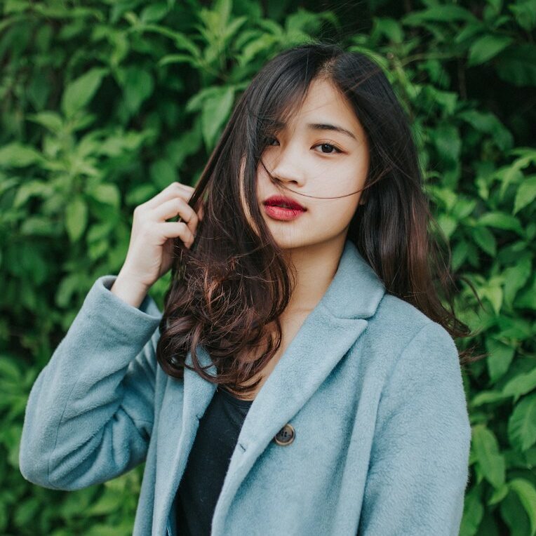 woman in gray coat standing near green plants